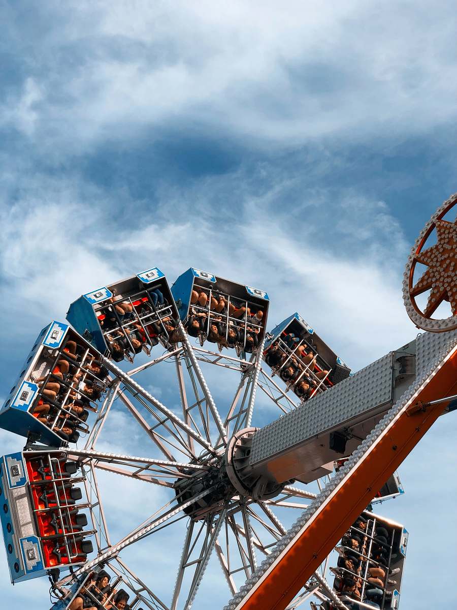 ferris wheel people sitting on rids under white clouds human